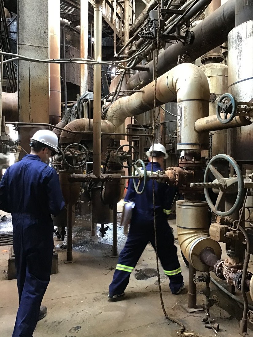Technicians walking down piping in a process plant